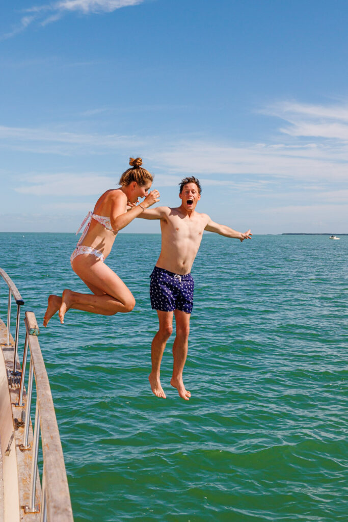 Jenn and Elliott jumping into the water in their swimsuits, one of the best gift ideas for boaters