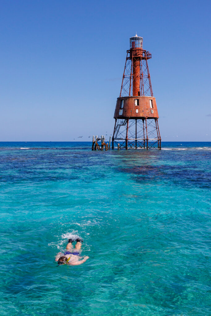 Elliot snorkeling in Florida in Key Largo with the Carysfort lighthouse behind him.