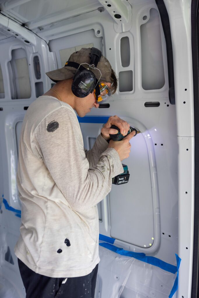 elliot drilling holes into the van with the drill and step bit